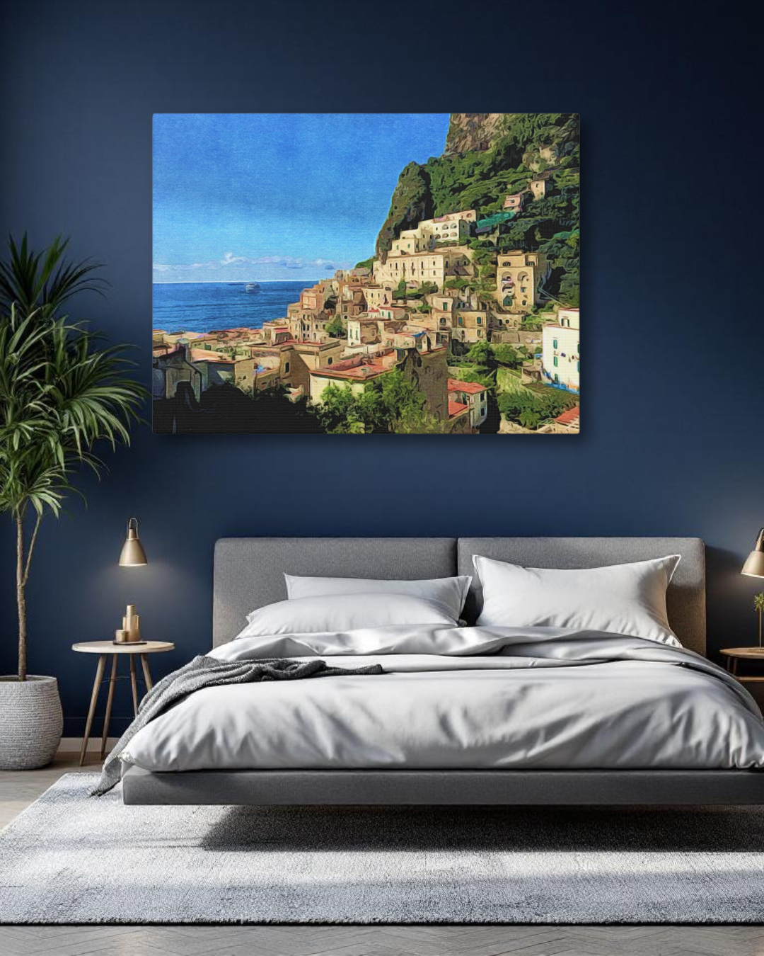 A large canvas print of the colorful hillside village of Positano on the Amalfi Coast, hanging on a dark navy blue bedroom wall above a modern grey bed.