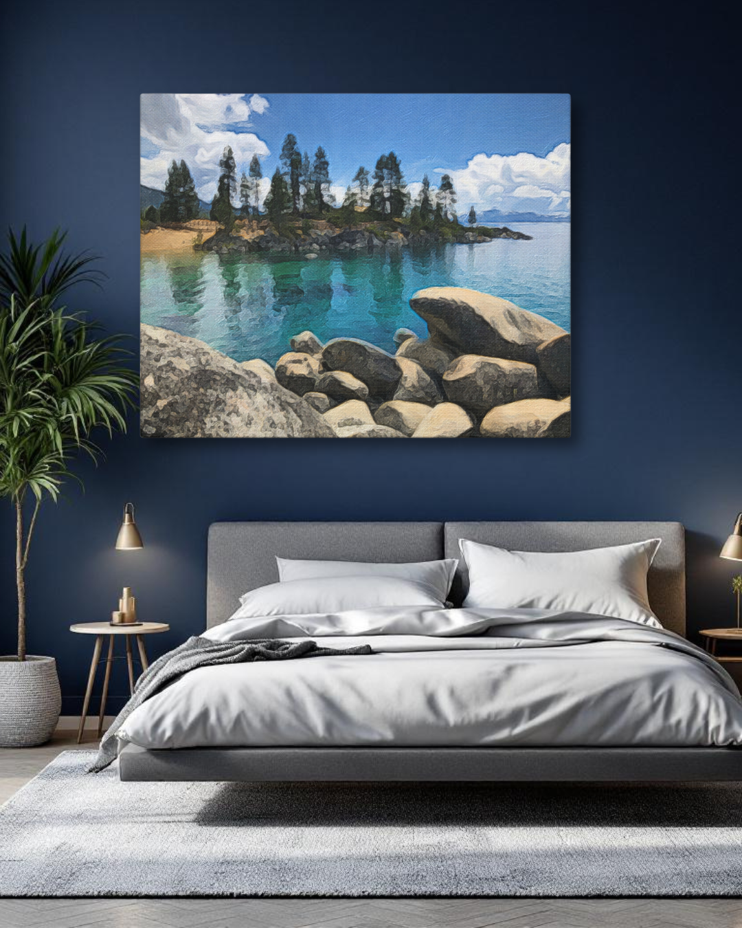 A lifestyle mockup image of a large Lake Tahoe watercolor canvas painting hanging above a grey upholstered bed in a bedroom. The deep navy blue wall contrasts with the vibrant turquoise water in the artwork, showing how it can be a tranquil focal point.