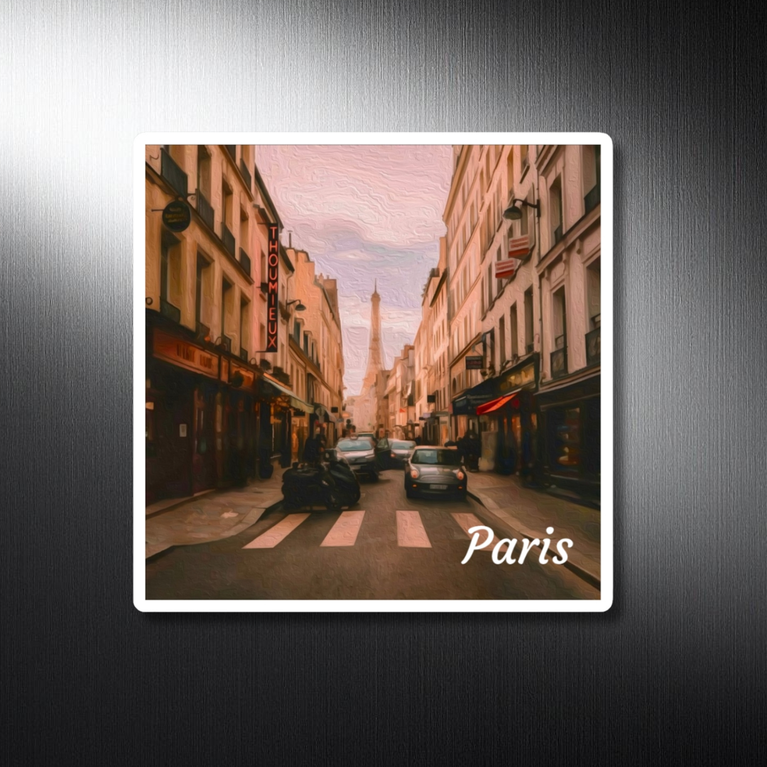 Square decorative travel magnet featuring a digital watercolor of a classic Parisian street scene with the Eiffel Tower framed between Haussmann buildings, warm amber evening light and the iconic Thoumieux restaurant sign, displayed on a brushed metal surface. Part of The Painted Passport Original Series.