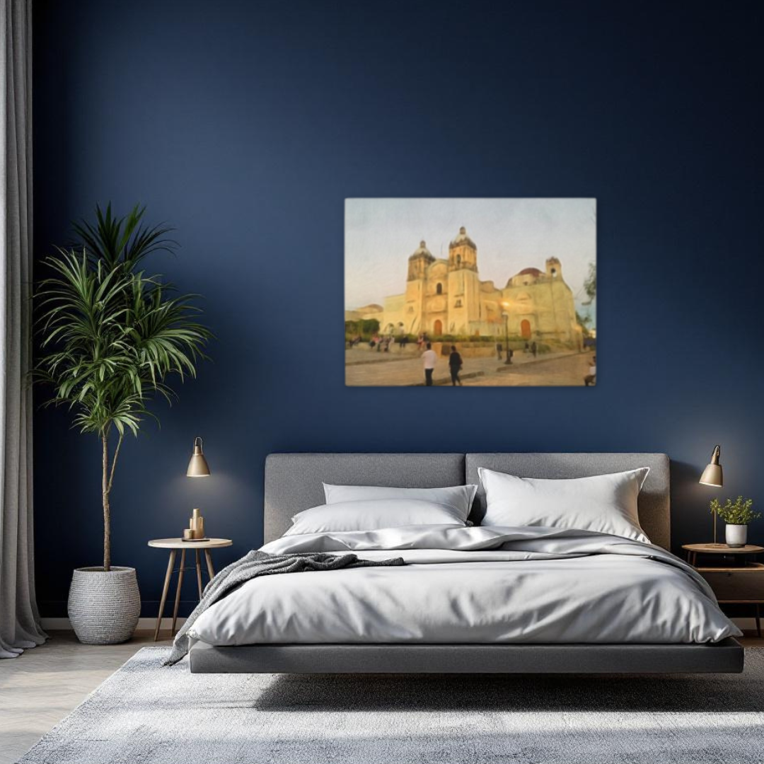 Wide view of a modern bedroom featuring a large watercolor canvas print of Templo de Santo Domingo in Oaxaca, Mexico. The room includes navy blue walls, a gray upholstered bed, and a large indoor potted plant.